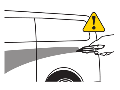 A hand carefully uses a cutting tool at the decal edge beside a yellow caution symbol.
